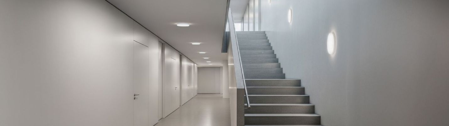 Ein Flur und Treppenaufgang mit Decken- und Wandleuchten