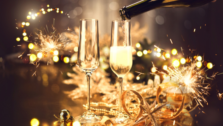 Zwei Sektgläser stossen aneinander umgeben von Glitzer