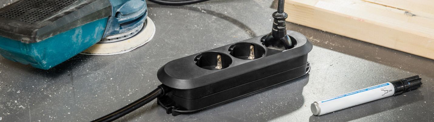 Eine schwarze Steckerleiste liegt neben Werkzeug
