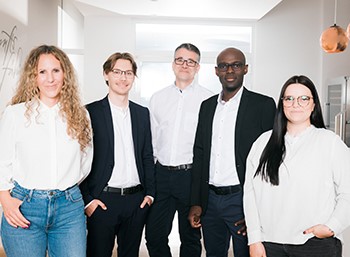 Gruppe von Menschen in Anzügen, Bild 2: Farbiger Mann mit Brille und Steckdosenleiste in der Hand