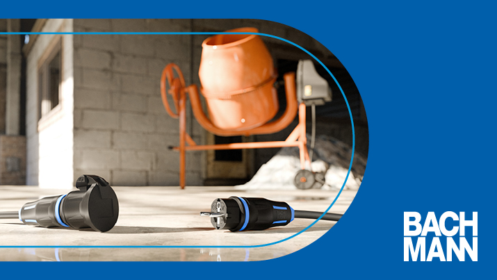 Zwei Kupplungen und Stecker liegen auf dem Boden vor einem Betonmischer