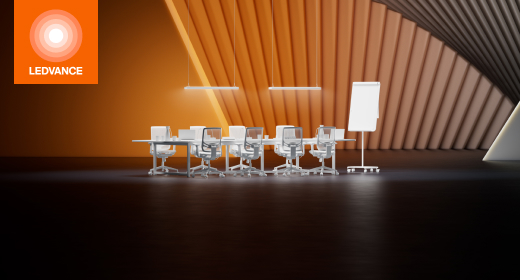 Eine weiße Sitzgruppe mit Tisch vor einem orangefarbenen fächerartigen Hintergrund