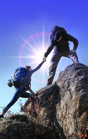 Bergsteiger zieht anderen Bergsteiger helfend mit Hand hoch